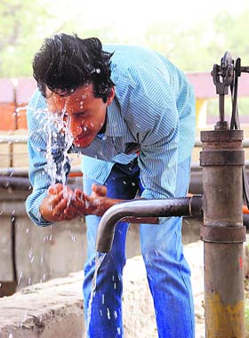 A passer-by splashes water on his face to beat the scorching heat near the Sirhind Canal in Bathinda
