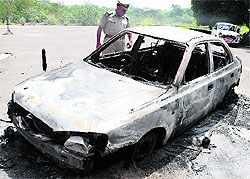 A policeman inspects the car that was set afire by protesting students
