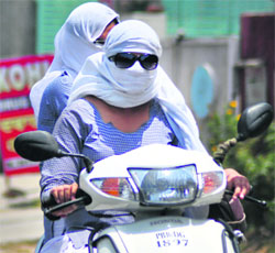 Girls ride a scooter with their faces covered to protect themselves from heat in Ludhiana on Saturday.