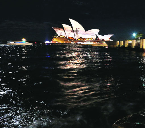 A ferry sails past as a photograph is projected onto the sails of the Sydney Opera House.
