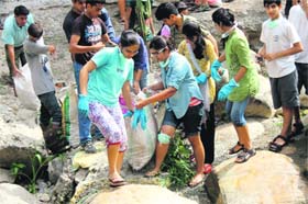 Volunteers of Making a Difference clean garbage from the Tamsa stream at Tapkeshwar temple in Dehradun on Sunday