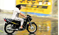 a motorcyclist is caught unawares during showers in Jammu on Sunday