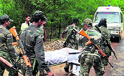 Security personnel carry a body at the site of Maoists' ambush on Sunday in Bastar where the Congress party's Parivartan Yatra was attacked on Saturday