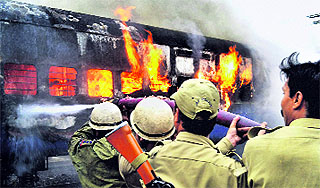 Firefighters try to control blaze aboard a train at the Jammu railway station on Sunday