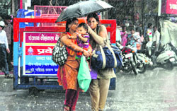Women take shelter under an umbrella as sharp showers lashed Dehradun on Monday. Tribune photo: Vinod Pundir