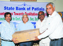 Dr KC Bhardwaj, Chairman, Board of School Education (centre) and chief manager Harish Khurana (left) give away ceiling fans to Ramesh Bura, Principal, Government Girls Senior Secondary School (extreme right), and block education officer Vinod Gaba in Bhiwani. 