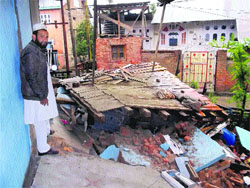A resident of Sartingal village in Bhaderwah stands near his collapsed house on Monday.