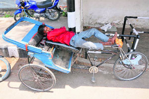 Nap time: A rickshaw puller takes a nap during his free time on the roadside in Jammu on Monday. 
