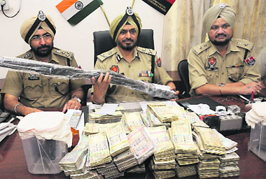 Inspector-General, Bathinda zone, Nirmal Singh Dhillon flanked by DIG AS Chahal (left) and Muktsar SSP Surjeet Singh shows the rifle and cash recovered from robbers, during a press conference in Bathinda on Tuesday. 