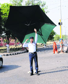 With a garden umbrella to protect himself from the sun, a policeman regulates traffic in Chandigarh. 