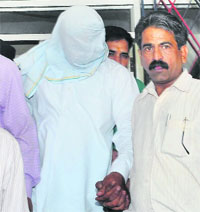 Accused ASI Devinder Kumar (face covered) in the custody of CBI officials in Chandigarh on Wednesday.