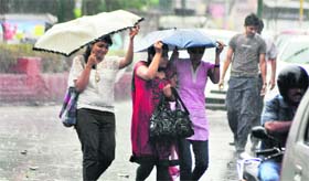 Girls protect themselves from rain that lashed Dehradun on Thursday
