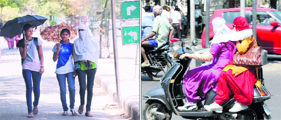 Girls use umbrellas and (right) cover their faces to save themselves from the scorching heat in Bathinda.