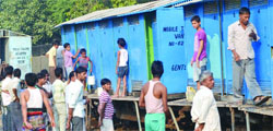 People queue up outside mobile toilets in a slum area. Tribune photo