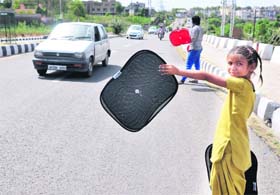 As mercury soars, Suman, a nine-year-old girl, sells sun shades to car owners on the Sher-e-Kashmir Bridge in Jammu on Friday