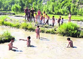 Fun time: Children play in muddy water in a rural area of north Kashmir to beat the sweltering heat in Srinagar on Friday