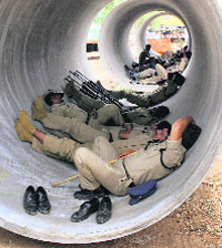 Policemen relax inside a huge pipeline in Hyderabad on Saturday.