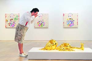 Japanese artist Takashi Murakami poses in front of one of his sculptures during a press preview of his solo exhibition at Galerie Perrotin in Hong Kong