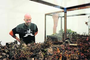 British artist Jake Chapman looks at his and his brother Dinos Chapmans art piece "The Sum of all Evil", which showcases numerous miniature Nazi soldiers in various states of diabolical torment, during a media preview at Hong Kongs White Cube gallery, as he unveiled the siblings first exhibition in China