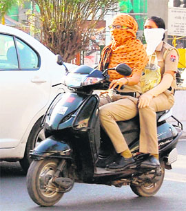 Policewomen ride a scooter with their faces covered on a hot day in Amritsar on Sunday.