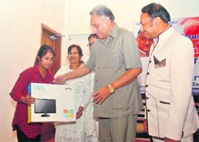 Uttarakhand Chief minister Vijay Bahuguna presents a computer to an official of "Karuna Ek Prayas", a voluntary organisation, in Dehradun on Sunday