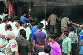 Residents gather outside the shop near Basti Jodhwal Chowk in Ludhiana where a fire broke out on Sunday