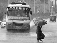 Pre-monsoon shower: A woman crosses a flooded road after rain lashed Jaipur on Monday