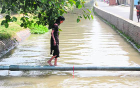 A girl makes her way across the Sirhind canal over a pipe on a hot sultry day in Bathinda on Tuesday.