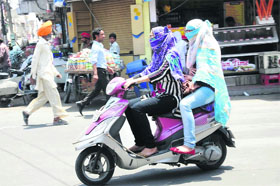 Girls cover their faces to protect themselves from heat while venturing out in Bathinda on Tuesday.