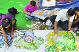 Artists from the Health Education and Environment Awareness Society make paintings on the roadside on the eve of World Environment Day in New Delhi on Tuesday.