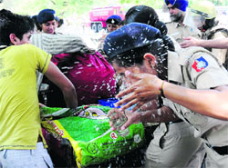 A woman constable splashes her eyes with water after being exposed to tear gas in front of the Congress Bhawan, Sector 15, Chandigarh, on Wednesday.