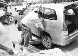 A wheel of a car stuck in a manhole at the Dera Bassi bus stand. 