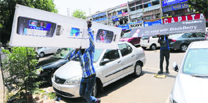 An MC worker removes a signboard at the Sector 22 market in Chandigarh on Wednesday.
