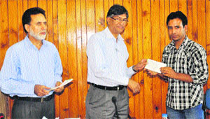 Kashmir University Vice-Chancellor Prof Talat Ahmad presents a scholarship cheque to a student in Srinagar on Wednesday. 