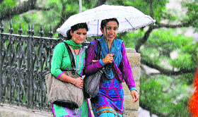 Girls hold an umbrella during sudden rain in Shimla on Thursday.