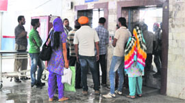 Patients and their attendants wait outside the only lift which is operational at the GMCH in Jammu on Friday.