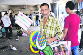 A man sells hand-made fans at the bus stand in Jammu on Friday.