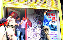 Policemen stand guard as an Enforcement Directorate team conducts a raid at the premises of a money changer in Jalandhar on Friday