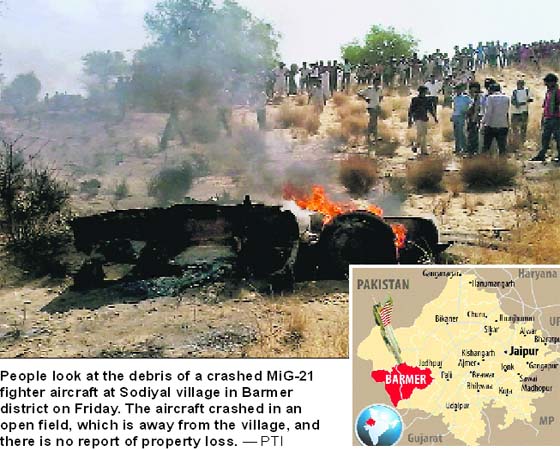 People look at the debris of a crashed MiG-21 fighter aircraft at Sodiyal village in Barmer district on Friday. The aircraft crashed in an open field, which is away from the village, and there is no report of property loss