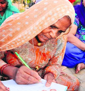 An elderly woman learning Hindi alphabets during a class at Azad Nagar Park in Bathinda