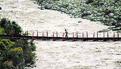 A boy crosses a bridge near the Mandi area in Poonch district. The bridge connects two parts of a village separated by a river