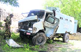 A CRPF personnel looks at the ill-fated vehicle at Sangri-Top in Sopore district on Saturday