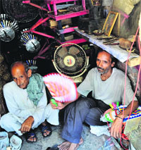 A shopkeeper uses a hand-made fan during a power cut in Jammu on Sunday. 