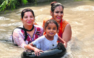 A family enjoys a dip in Ranvir Canal to fight the heat in Jammu on Sunday. 