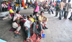 Passengers wait for buses at the general bus stand in Jammu on Monday.