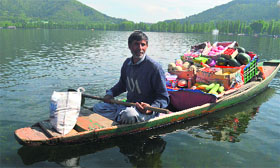 A man in a shikara sells fruits to local residents and tourists at the Dal Lake in Srinagar on Monday.