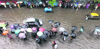 People wade through a flooded street after a heavy downpour in Mumbai on Monday.