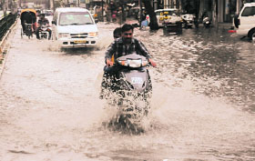 A scooterist cautiously makes his way through accumulated rainwater.