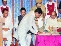 Maharashtra Governor K Shankarnarayan (R), CM Prithviraj Chavan and Deputy CM Ajit Pawar (L) look on as NCP leader Dilip Sopal signs a paper during the swearing-in ceremony at Raj Bhawan in Mumbai on Tuesday