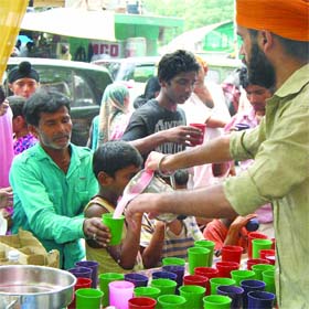 Sikh devotees serve sweet water to people on the occasion of Martyrdom Day of Guru Arjan Dev at Bangla Sahib Gurdwara in New Delhi on Wednesday